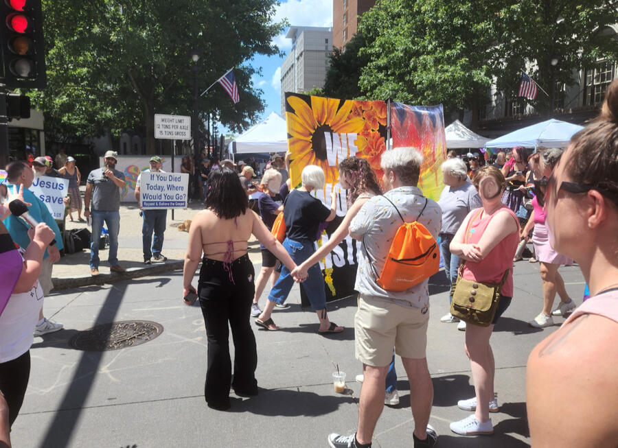 A pile of laminated paper signs, three of which show artist's statements for individual works, and one of which is an overall explanation of the project. a photo of all three current barriers is the background